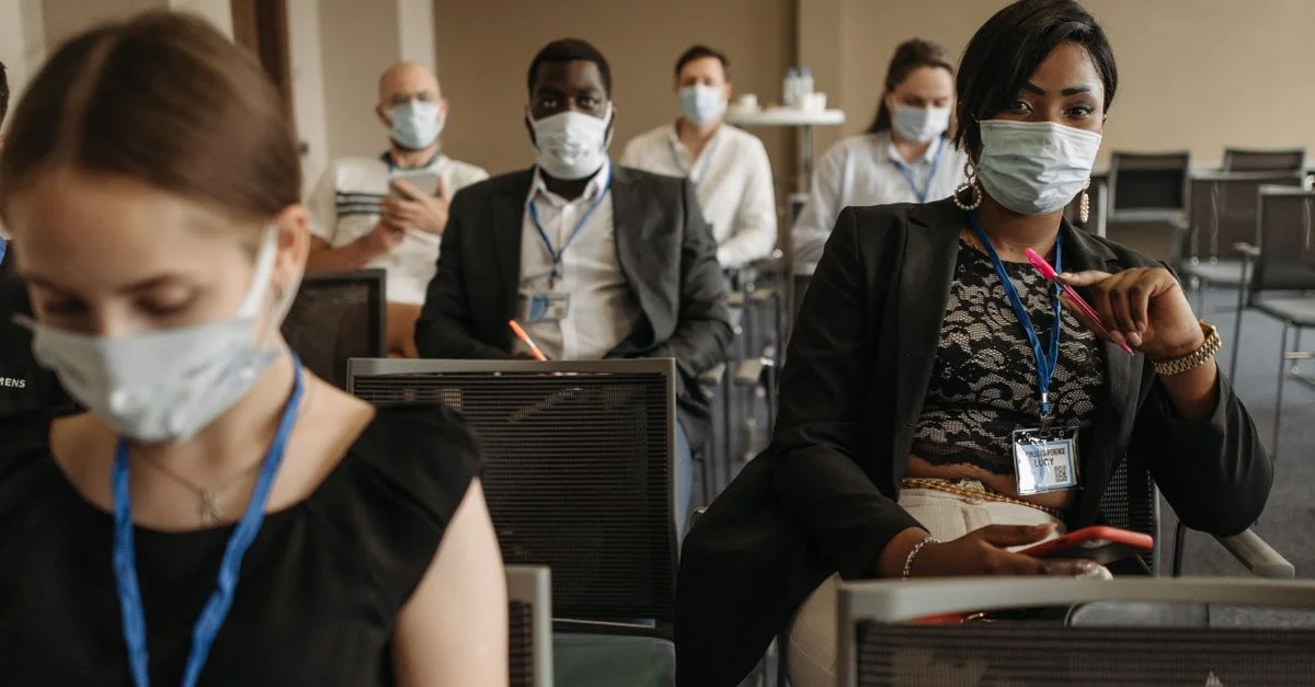 Des participants à une conférence d'affaires portant des masques soulignant le nouveau normal et la diversité dans les réunions modernes.