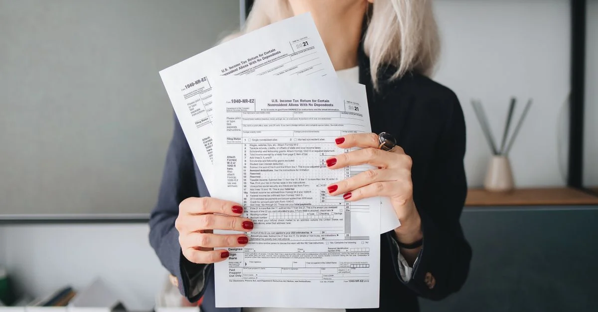 Femme d'affaires tenant des documents fiscaux, prête à être déposée ou examinée, dans un cadre de bureau professionnel.